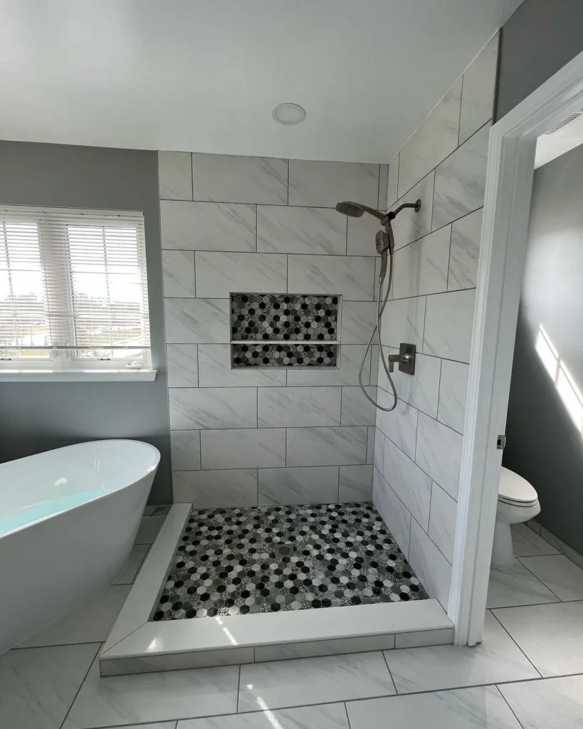 38 Bathrooms With Hexagon Tile Floors 29 A Chic And Sophisticated Bathroom Featuring Hexagonal Tiles In A White And Light Grey Color Scheme On The Floor, Creating A Subtle Yet Stylish Pattern. A White Tub Is Situated In The Center Of The Room, Surrounded By The Hexagonal Tiles, Creating A Stunning Focal Point. A White Toilet Is Located Off To The Side, Providing Functionality And Convenience.