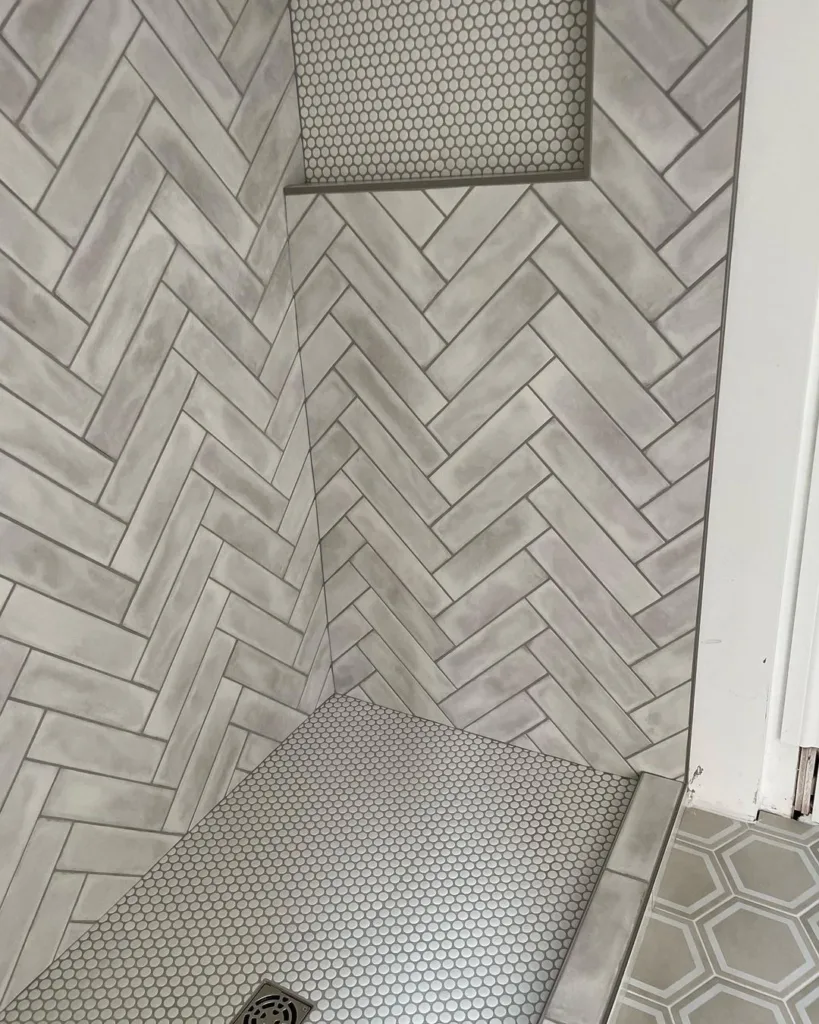 38 Bathrooms With Hexagon Tile Floors 31 &Quot;A Stylish And Modern Bathroom With A Color Palette Of Grey And Cream. The Walls Are Covered In Large Rectangular Tiles In Shades Of Grey And Cream, Providing A Subtle And Calming Backdrop To The Space. The Floor Features A Small Hexagonal Tile Pattern In Shades Of Grey, Adding Texture And Interest To The Design.